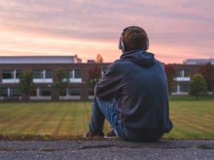 teenager looking out over field with headphones